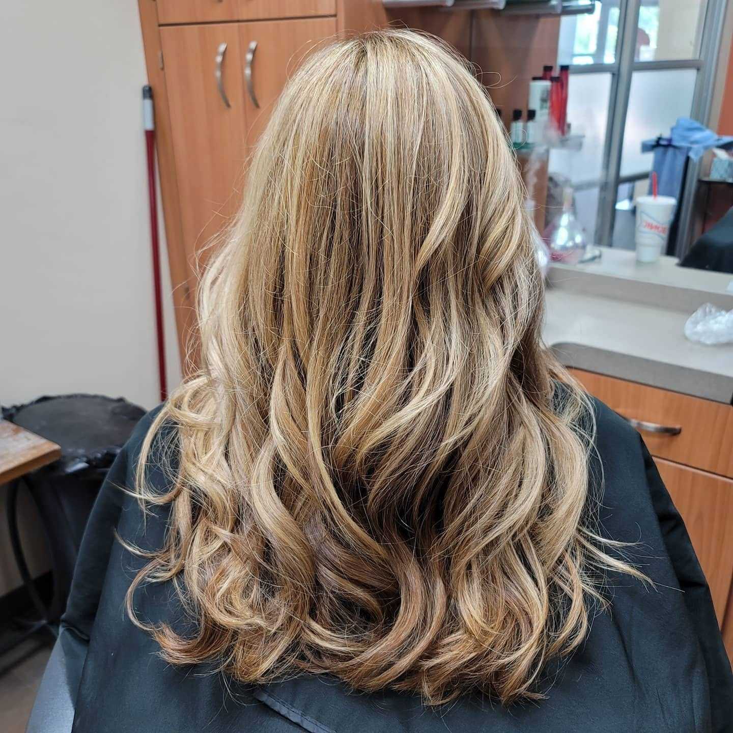 Blonde hair with loose curls in a salon setting.