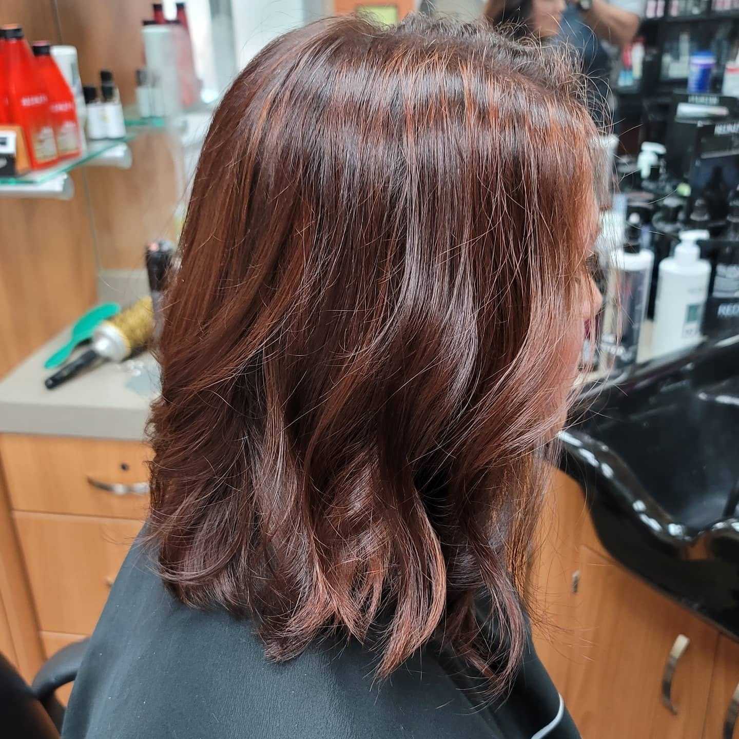 Newly styled brown hair with soft waves in a salon setting.